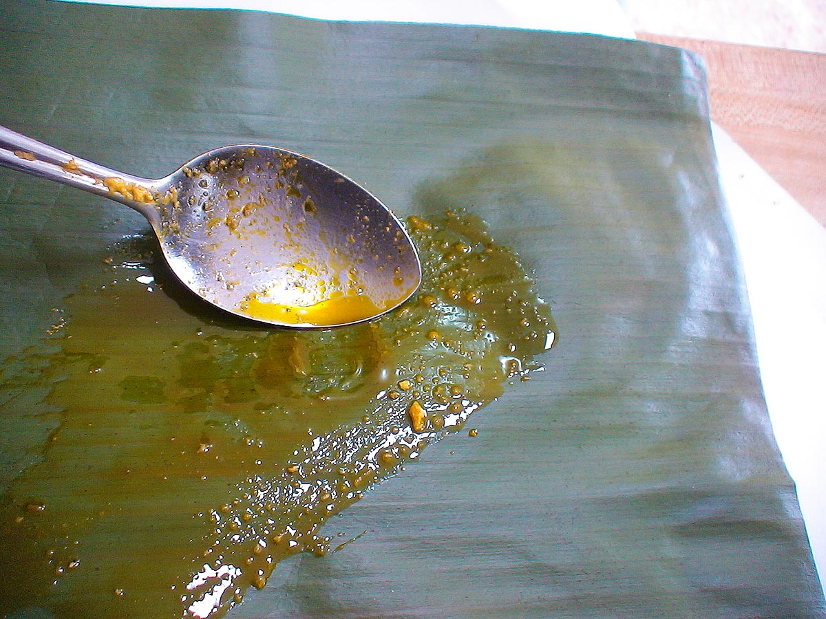 Spreading annatto oil on banana leaf